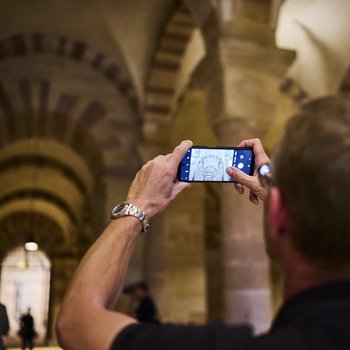 Mann fotografiert in Krypta mit Smartphone